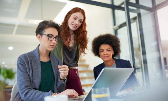 Three women are looking at a computer screen during EHR implementation.