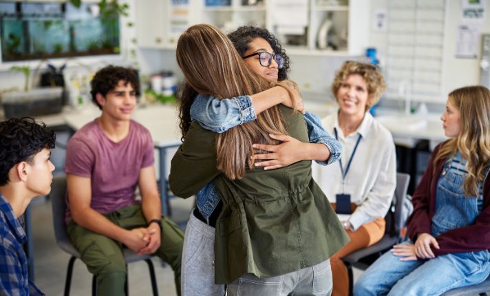 A student is getting a hug in a support group from a student mental health resources list.